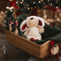 Cozy Dinkums Bunny Twiggy lying inside a festive pull along basket