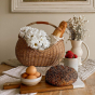 Olli Ella half moon wicker basket on a wooden table filled with some white flowers and bread