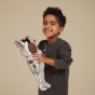 Child smiling, holding a Olli Ella Zebra mini Cozy Dinkum Doll 
