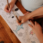 Two children colour in the Olli Ella Playpa Children's Colouring Paper Roll Travel Pack  -  Ocean Design in a home setting.