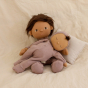 Olli Ella plush Dozy Dinkum doll laying across an Olli Ella Dinkum doll on a cream background