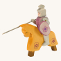 The Ostheimer Wooden Toy Red Riding Knight, handpainted with grey armour and a purple-red shield with a flower coat of arms. The knight is holding a sword and lance, riding a horse with a yellow cover.