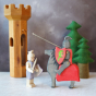 The Ostheimer Wooden Black Knight's Horse Toy with Riding Black Knight (available separately) with trees and a wooden tower in the background