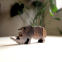 Close up of O-WOW sustainable dark oak Rhino toy on a white floor in front of some green plants