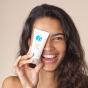 Person holding a tube of the OY! Clear Skin Cleansing Moisturiser smiling 