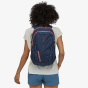 Picture of a female model wearing Patagonia Refugio backpack on their back. Background of picture is white. Colour of backpack in picture is navy. This colour is not sold on website. Colour used for style reference only. 