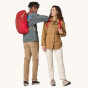 Two people wearing Patagonia Recycled Black Hole Backpack 25L in Touring Red showing front and rear view on a cream background 