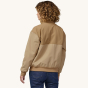 A woman models the back of the Patagonia Women's Shelled Synchilla Jacket - Tinamou Tan.