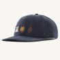 Patagonia Corduroy Baseball Cap - Channel Islands / Smolder Blue, on a cream background. On the front of the hat is an embroidered white rabbit, a yellow sun, and a golden plant.