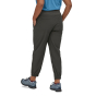 Patagonia Women's Happy Hike Studio Pants in Ink Black with stretchy waistband and ankle cuffs & side pockets worn by a person wearing a blue top and hiking shoes on a white background