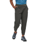 Patagonia Women's Happy Hike Studio Pants in Ink Black with stretchy waistband and ankle cuffs & side pockets worn by a person wearing a blue top and hiking shoes on a white background