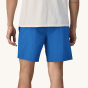 A back, close up of an adult wearing the Patagonia Men's Baggies Lights - Endless Blue. Mid-Blue baggy men's shorts, and a white t-shirt on a cream background