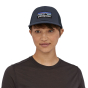 Close up of a woman wearing the Patagonia recycled plastic P6 trucker cap in the navy colour on a white background