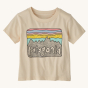 Patagonia Little Kids Fitz Roy Skies T-Shirt - Undyed Natural. A lovely cream colored t-shirt with fun Patagonia mountain range print in front of a striped pink, blue and yellow sky