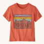 Patagonia Little Kids Fitz Roy Skies T-Shirt - Coho Coral. A light coral t-shirt with a fun Patagonia mountain range print in front of a pink, blue and yellow striped sky