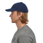 Close up of man stood sideways on a white background wearing the classic navy Patagonia P-6 label trad cap  