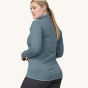A woman models the back of the Patagonia Women's R1 Daily Jacket - Light Plume Grey / Steam Blue X-Dye against a plain background.