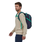 A man wearing the Patagonia Refugio Day Pack 26L - Classic Navy/Fresh Teal, stood upright, front side view, on white background