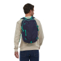 A man wearing the Patagonia Refugio Day Pack 26L - Classic Navy/Fresh Teal, stood upright, front back view, on white background