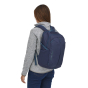 A woman wearing the Patagonia Refugio Day Pack 26L - Classic Navy, stood upright back top view, on a white background