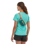 A person wearing the The Patagonia Ultralight Black Hole Mini Hip Pack - Patchwork: Current Blue, around body from their left shoulder to right waist, stood upright, rear facing on a white background