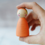 Peepul plastic-free handmade wooden carrot peg doll toy with adult hand for scale.