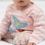 close up of a child wearing soft pink organic cotton 3-piece baby set with the little lamb print  from piccalilly