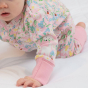 close up of a baby wearing soft pink organic cotton romper with the little lamb print from piccalilly