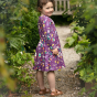 A young child wears the Piccalilly Long Sleeve Skater Dress - Science in an outdoor setting.