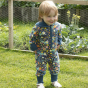 Young child stood on some grass wearing the Piccalilly organic cotton hooded galaxy playsuit