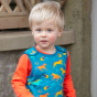 close up of a child wearing blue organic cotton dungaree with the colourful wild horses print from piccalilly