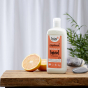 Bio-D vegan friendly Pink Grapefruit scented Washing Up Liquid in a 750ml bottle on a wooden table with cut grapefruits, and a white back ground