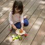 Child outside on decking cutting up pretend play food from the PlanToys Assorted Fruit Set.