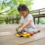 Toddler playing with the PlanToys assorted vegetable set outside on wooden decking. 