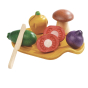 The PlanToys Assorted Vegetable set is a play food set for toddlers and includes a mushroom, courgette, red onion, yellow pepper and red tomato, wooden knife and chopping board. White background.