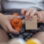 Child twisting PlanToys Wooden Nuts and Bolts Orange Tap Handle into a wooden block