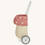 Olli Ella rattan luggy with wheels, in the shape of a mushroom with white spots on a pale pink background.