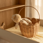 The Olli Ella Rattan Tulip Carry Basket - Natural holding a dozy Dinkum on a baby changing table