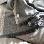 Close up of a Respiin dark grey woollen throw draped on a grey sofa