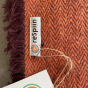 Close up of the Respiin label on the orange recycled wool throw blanket