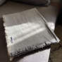 Respiin light grey recycled wool throw folded on a grey sofa