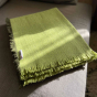 Green Respiin recycled wool blanket folded on a grey sofa