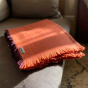 Respiin orange woollen throw blanket folded on a grey sofa