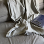 Respiin light grey woollen throw draped over a sofa with an iPad and reading glasses on top