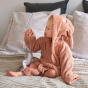 Young toddler sat on a white bed wearing the organic cotton Roommate bunny bath robe