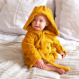 Toddler sat on a white bed wearing the organic cotton Roommate tiger bath robe