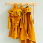 Roommate kids organic cotton hooded tiger towel and bathrobe hanging from a wooden hook on a grey wall