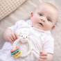 A child laid down on a light coloured blanket, with the Sophie la Girafe® - So'Pure Multi-textured Sensory Teether Ring on their tummy
