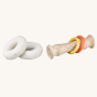 A look at how the different pieces can be removed from the Sophie The Giraffe So Pure Totum Rattle, to give endless play options. The large white ends and rings are removable from the Totum pole. Image is on a cream background