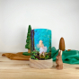 Toverlux Light Wishes Base and Silhouette in Star Money. A beautiful felt illustration o a child ina  white dress, looking up at golden stars. The Light Wish is set on a wooden table with a wooden rabbit in front, green and brown fabric behind with wooden